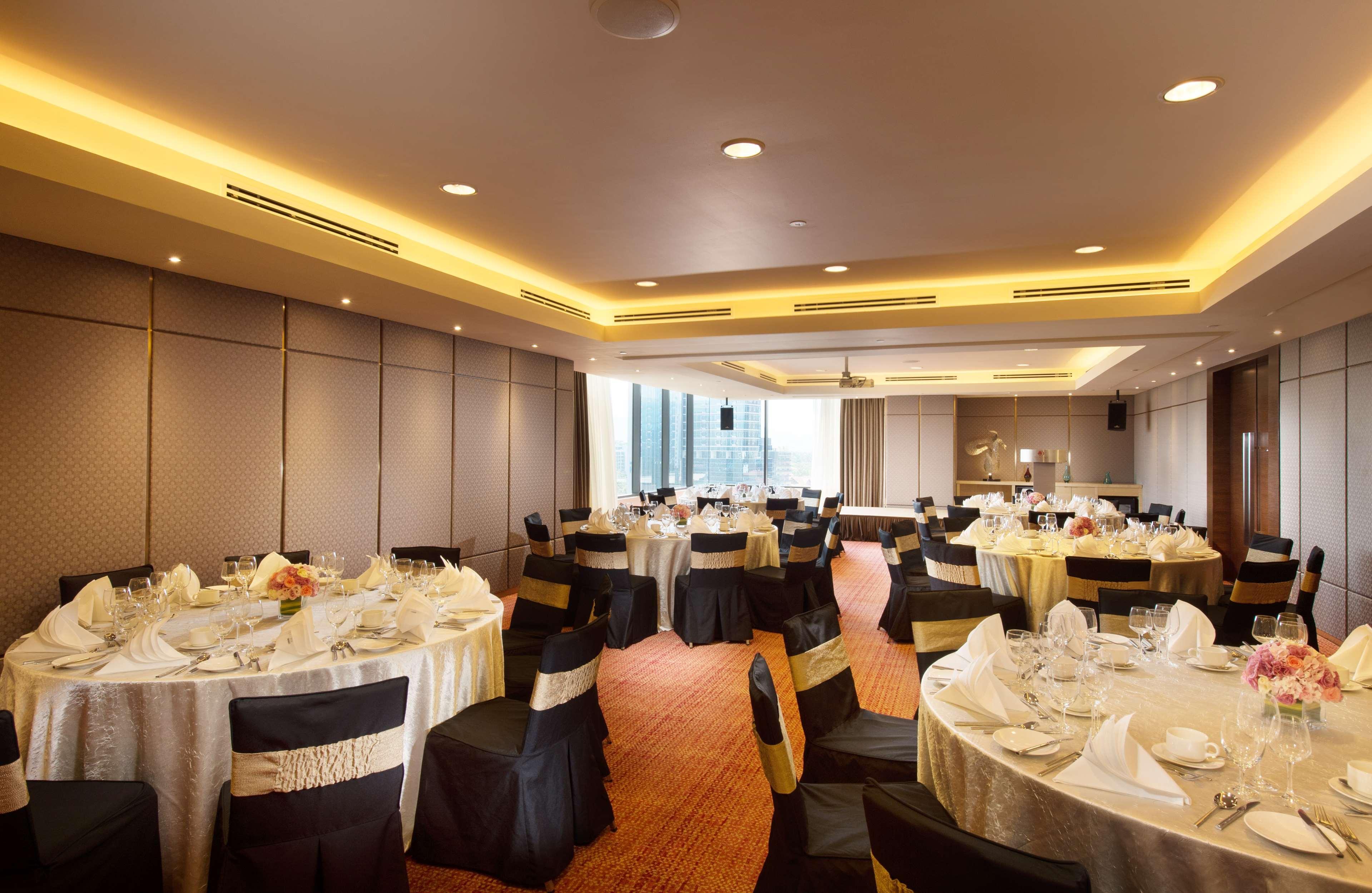 Doubletree By Hilton Kuala Lumpur Hotel Kültér fotó The photo depicts a decorated banquet hall or event space. There are several round tables set with white tablecloths and black chair covers, some adorned with gold sashes. Each table is elegantly arranged with tableware, including plates, glassware, 