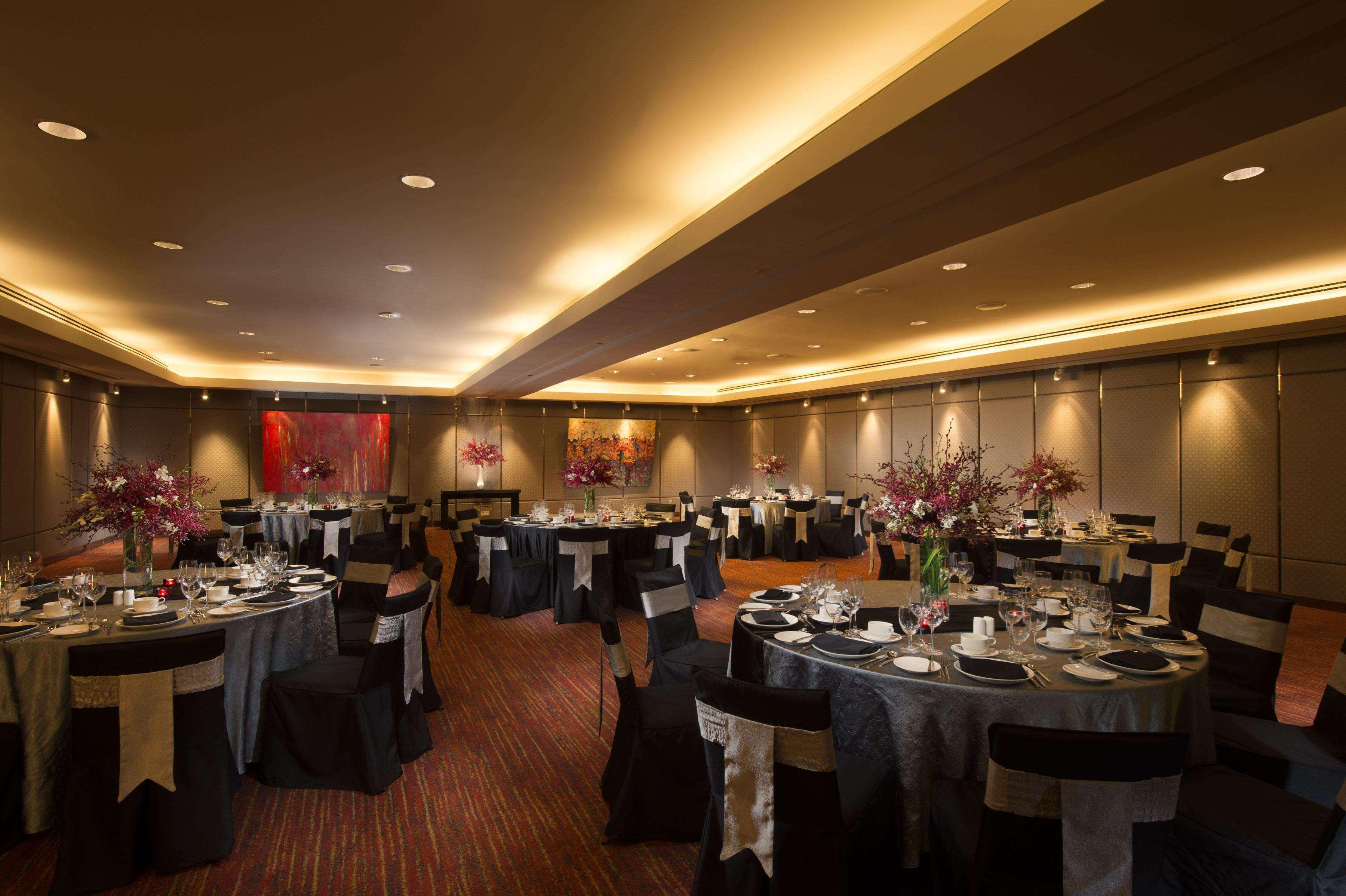 Doubletree By Hilton Kuala Lumpur Hotel Üzleti fotó The photo depicts an elegantly designed event space or banquet hall. It features several round tables covered with black and silver tablecloths, each set with plates, glassware, and utensils, suggesting a formal dining setup. 

The room is well-lit w