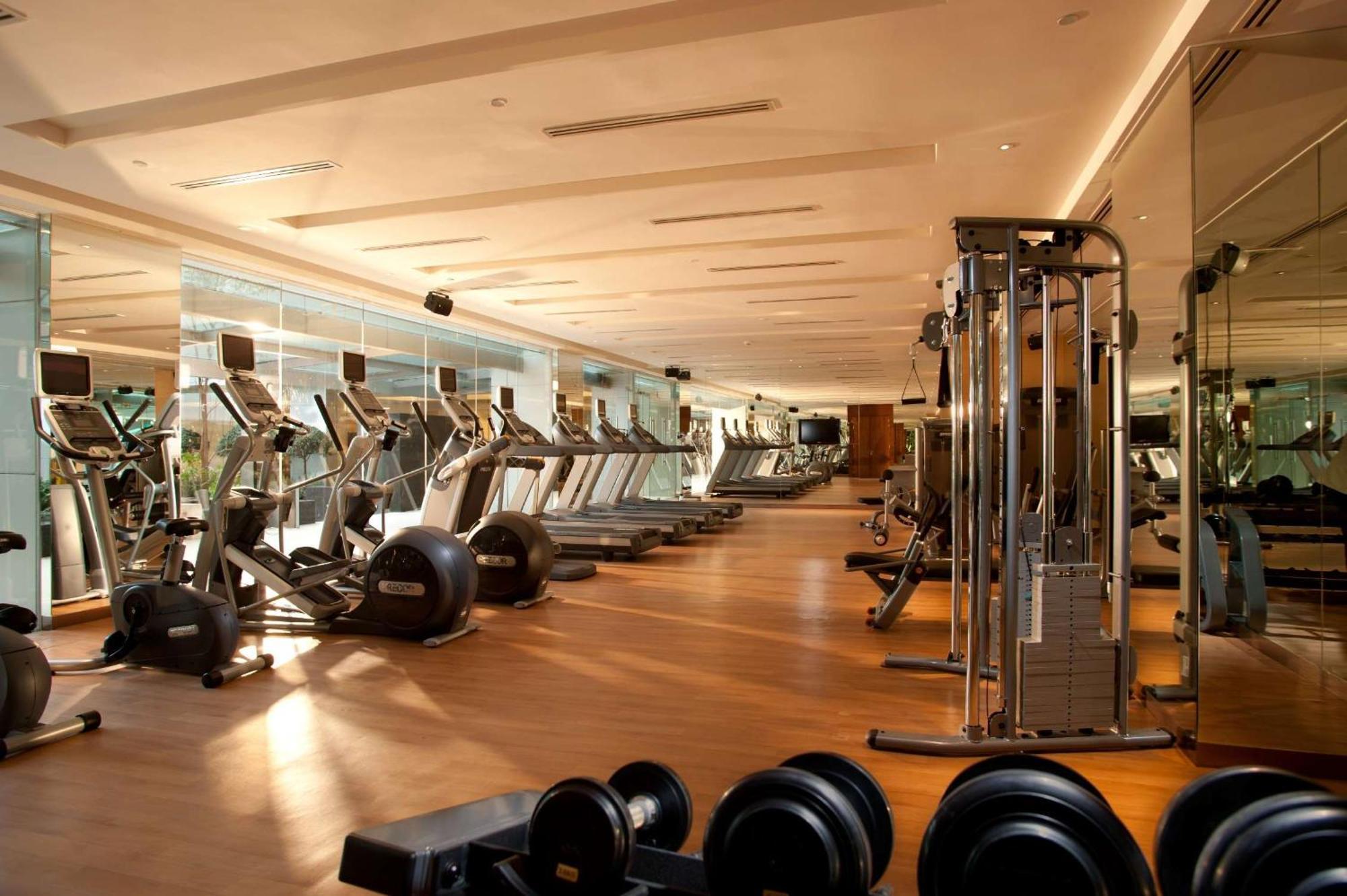 Doubletree By Hilton Kuala Lumpur Hotel Kültér fotó The photo shows a modern gym interior. It features various fitness equipment including treadmills, exercise bikes, and weight machines. The gym has a spacious layout with large windows that allow natural light to enter, creating a bright and inviting