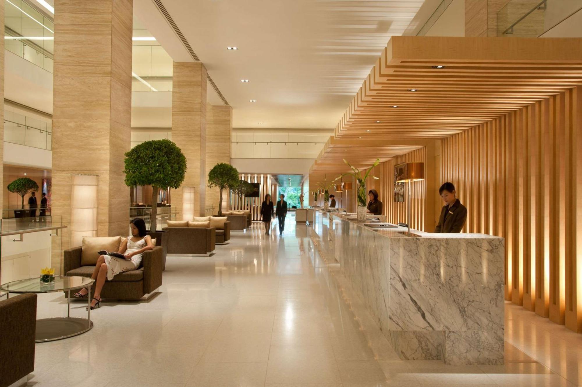 Doubletree By Hilton Kuala Lumpur Hotel Kültér fotó The photo shows a modern hotel lobby. It features a spacious, well-lit area with high ceilings and elegant design elements. The reception desk, made of marble, is positioned prominently, with staff members attending to guests. There are several comfo